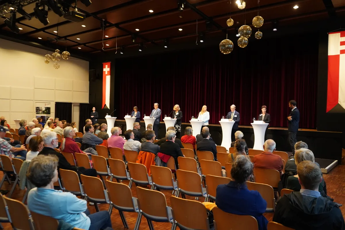 Zahlreiche Stuhlreihen in einem grossen Saal, viele Sitze sind leer.